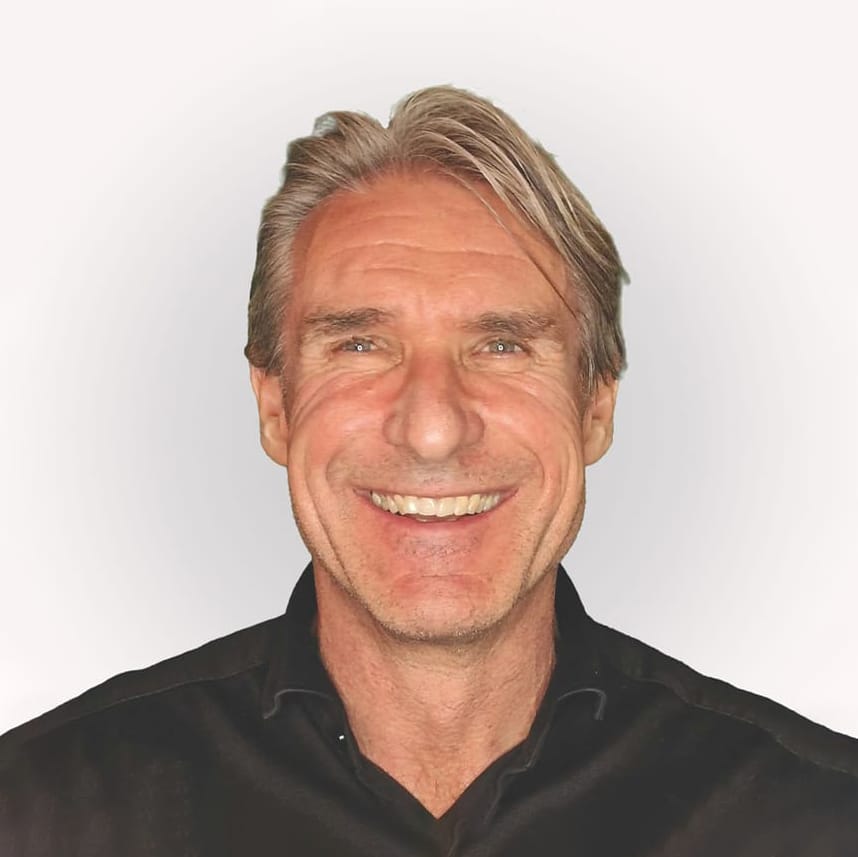 Mann mittleren Alters mit grauem Haar, lächelnd in schwarzem Hemd vor hellem Hintergrund.