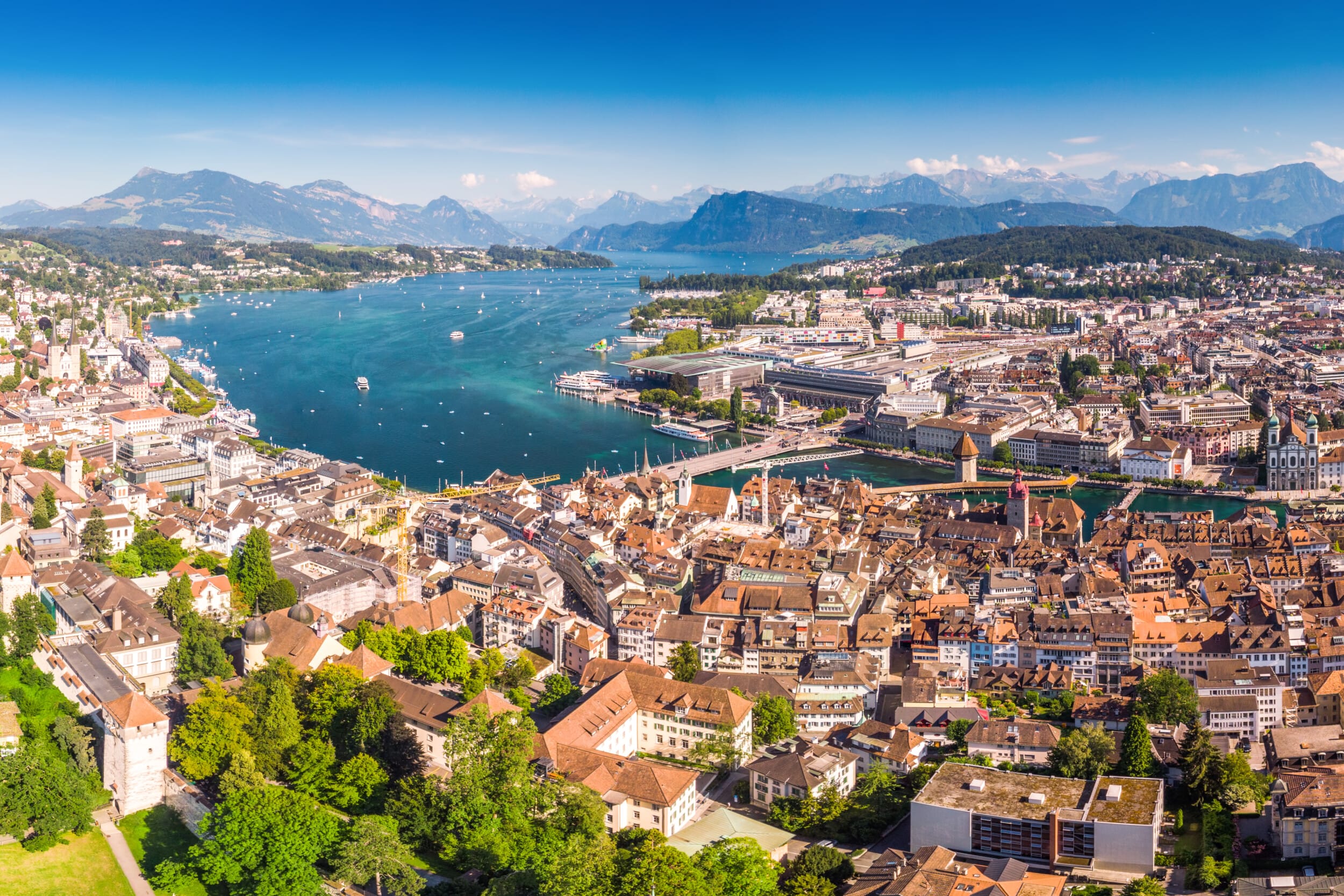 Panorama von Luzern mit historischen Gebäuden, blauem See und Bergen bei Sonnenschein.